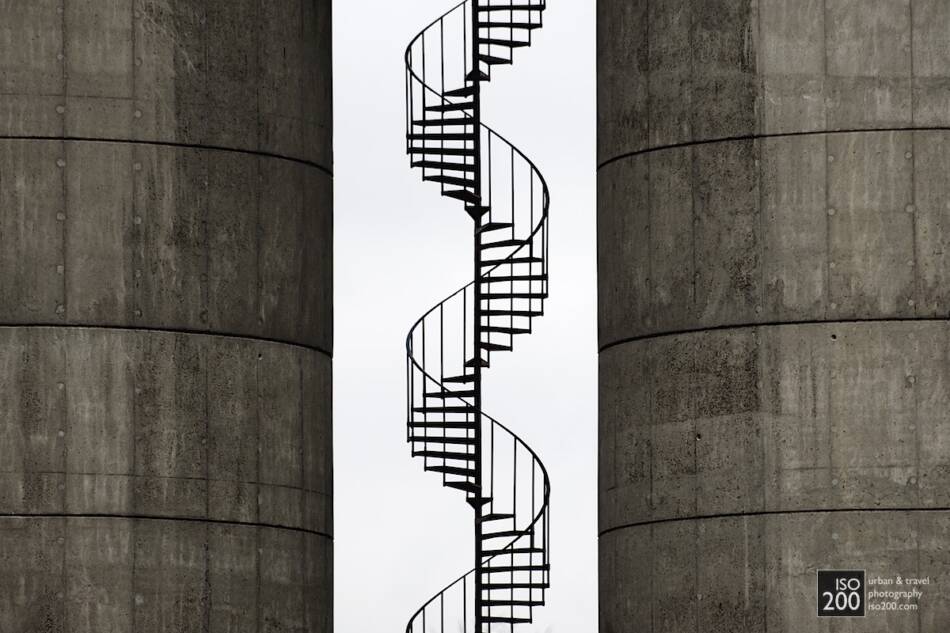 Photo of a spiral metal staircase between concrete tanks, Copenhagen.